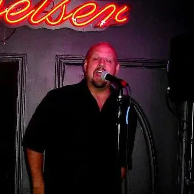 Man singing into a microphone under a neon sign at the MOON MUTT Recording Studio. | MOON MUTT Recording Studio