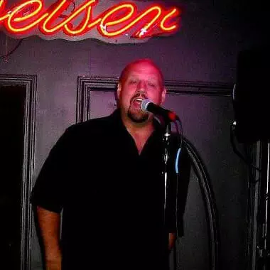 Man singing into a microphone under a neon sign at the MOON MUTT Recording Studio. | MOON MUTT Recording Studio