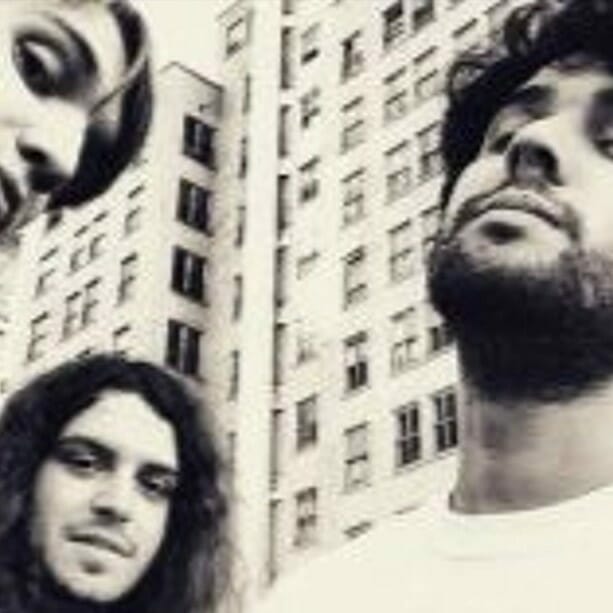 Alternative rock band 95 Behind with different expressions standing in front of a building with windows. | MOON MUTT Recording Studio